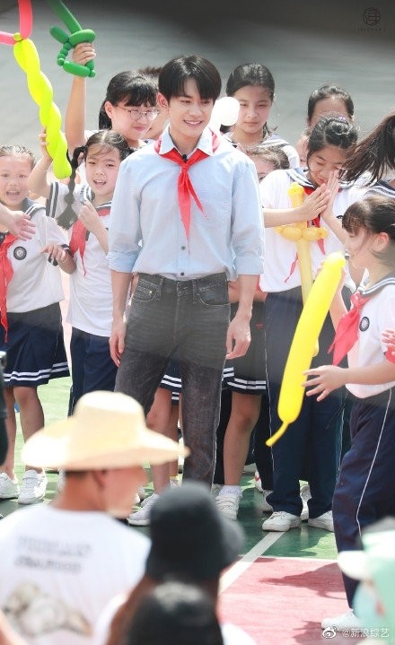 易烊千玺活动路透清爽帅气，蓝色衬衣戴红领巾化身校园学长